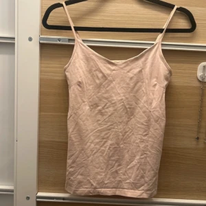 Rosa  linnetopp - Säljer en stilren rosa linnetopp med smala axelband och v-ringning. Perfekt för varma sommardagar eller som ett basplagg i garderoben.