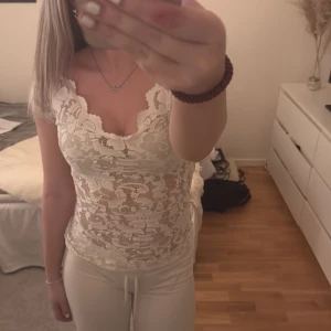 Vit spetstopp - Säljer en så fin vit spetstopp från Gina Tricot. Toppen  är ärmlöst och har en v-ringad design som ger en elegant touch. Perfekt för att klä upp en outfit eller bära som det är. Storlek Xs. Skriv för fler bilder🤍