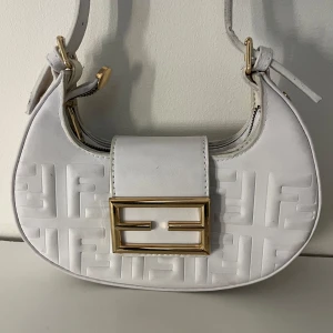 Vit axelväska med gulddetaljer - Snygg vit axelväska med ett elegant mönster och gulddetaljer. Perfekt för att ge din outfit en lyxig touch. Har en liknande i brunt på min sida.