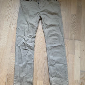 Beige montén byxor  - Snygga beige Jeans/Chinos med en klassisk design. De har en rak passform och är tillverkade i ett bekvämt bomullsmaterial. Perfekta för en stilren look. Storlek W30 L32
