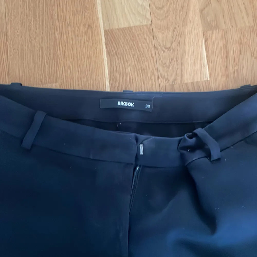 Klassiska svarta kostymbyxor från Bik Bok med normal passform och raka ben. Byxorna har hällor för bälte och stängs med dragkedja och hake. Perfekta till en stilren look.. Farkut & Housut.