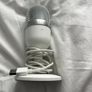 Vit USB-mikrofon från Razer - Säljer en stilren vit USB-mikrofon från Razer med rund metallgrill och stabil rund bas. Mikrofonen ansluts via USB och har en modern design som passar perfekt för streaming, podd eller gaming.