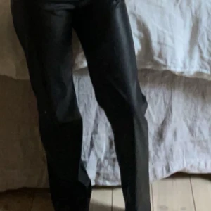Svarta skinnbyxor med rak passform - Säljer ett par svarta skinnbyxor med rak passform. Byxorna har en klassisk look och är perfekta för att lyfta vilken outfit som helst. Snygga att styla med både t-shirt och skjorta.