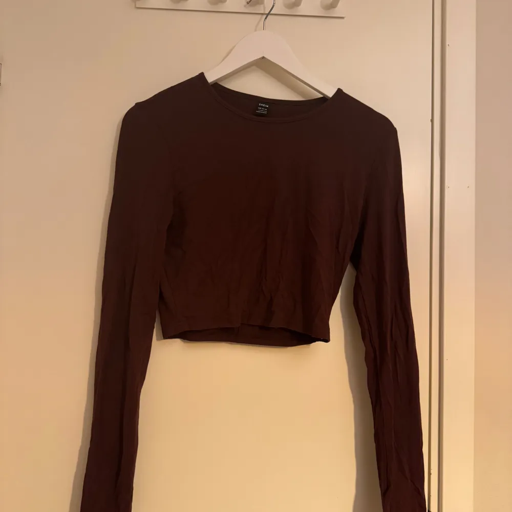Mörkbrun croppad topp från SHEIN med långa ärmar och rund halsringning. Enkel och stilren design som passar perfekt till jeans eller kjol. Mjuk och stretchig bomullsblandning för en bekväm känsla.. Yläosat.
