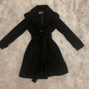 Super snygg svart kappa - Säljer denna jätte fina knälånga svarta kappan i storlek xs. Den är köpt secondhand men har blivit kemtvättad. Den är i ett bra skick.