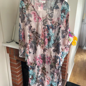 Blommig långklänning från Branting - Säljer en luftig och romantisk långklänning från Branting med blommigt mönster i rosa, blått och grått. Klänningen har v-ringning och trekvartsärm, perfekt för sommarens alla tillfällen.