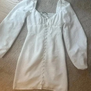 Klänning  - Supersöt vit kortklänning från Gina Tricot med långa puffärmar, knappar framtill och söt knytning vid bysten. Perfekt för studenten eller en skol avslutning🥰 pris kan diskuteras☀️