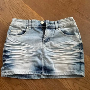 Blåvit lågmidjad jeanskjol  - Snygg ljusblå lågmidjad jeanskjol med coola vita detaljer. Skriv för bilder på, pris kan diskuteras! Midjemåttet tvärs över midjan är ungefär 35cm💓