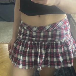 Rutig kortkjol i rött och vitt - Supersöt mini kjol rutig  i rött, vitt och blått. Kjolen har en bred linning och ett utställt, volangigt fall. Passar till många olika toppar och sneakers. 💞