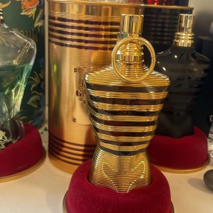 Jean Paul Gaultier la Male elixir  - Exklusiv herrparfym i en lyxig guldfärgad flaska formad som en manlig torso med horisontella ränder. Flaskan står på en röd sammetsbas och rymmer 75 ml. Doften är intensiv och elegant, perfekt för dig som vill sticka ut. Mängden kvar synd i andra bilden (65ml).