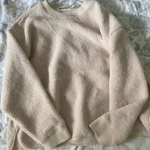 carin wester teddy hoodie - Mysig beige fleece-tröja från Carin Wester med rund halsringning och ribbade muddar vid ärmslut och hals. Perfekt för kyliga dagar och enkel att matcha med det mesta. Oversized passform för extra komfort.