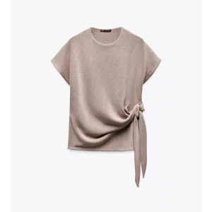 Beige topp med knyt - Snygg beige topp från Zara med korta ärmar och knyt i sidan. Toppen har rund halsringning och är tillverkad i ett mjukt material som ger en avslappnad men stilren look. Endast använd 1 gång därav pris, super fin men kommer tyvärr inte till användning. Pris kan diskuteras 