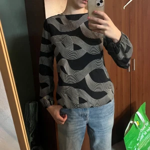 Svartvit blus med grafiskt mönster och knytband - En jättefin mönstrad blus från sisterpoint med band som kan knytas på lite olika sätt. För liten för mig, men passar perfekt för lite finare tillsättningar. Använd men i gott skick🥰