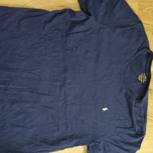 Mörkblå t-shirt från Ralph Lauren - Säljer en klassisk mörkblå t-shirt från Ralph Lauren med liten broderad logga på bröstet. T-shirten har rund hals och korta ärmar, perfekt till vardags. Enkel och stilren design.