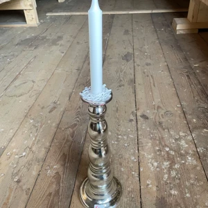 Silverfärgad ljusstake i metall - Snygg och klassisk ljusstake i silverfärgad metall med rundad form. Perfekt som stilren inredningsdetalj till hemmet. Passar vanliga kronljus. Ca 35 cm hög.