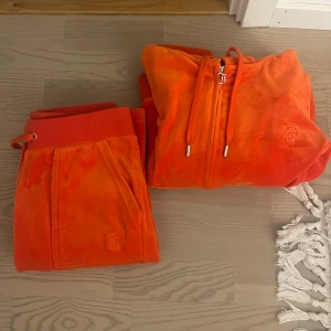 Orange mjukisbyxor från Juicy Couture - Säljer ett par orangea mjukisbyxor från Juicy Couture i supermjuk velour. Byxorna har resår i midjan, fickor och broderad JC-logga framtill. Perfekta för en chill och färgstark look.