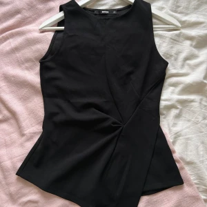 Fest topp från Bikbok XS💕 - Säljer ett svart linne med ”knut” på magen💞