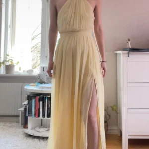 Ljusgul långklänning med slits - Säljer en jättefin ljusgul långklänning med halterneck och öppen rygg med pärldetaljer💗Klänningen har ett plisserat tyg och en hög slits framtill som ger en elegant känsla. Perfekt för bal eller sommarens speciella tillfällen.Klänningen är i mycket bra skick och normal i storleken, perfekt längd om du ska ha klackar och är runt 160+. Köpt från Vinted, och säljer igen då den inte passade💗 Postar så fort jag kan!  (lånade bilder) 