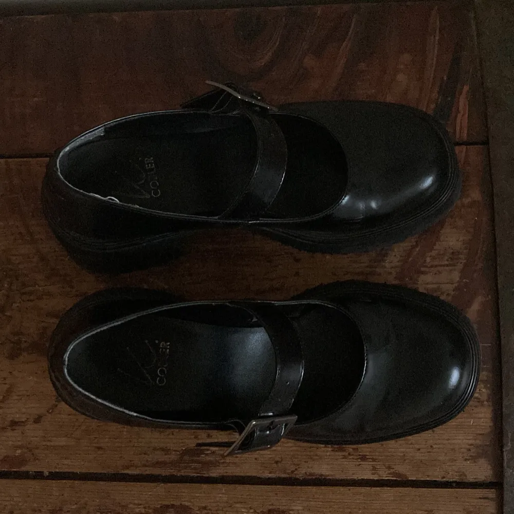 Säljer ett par chunky svarta Mary Jane skor med bred klack och silverfärgat spänne. Skorna har rund tå och platt sula, perfekta för dig som gillar en edgy och stilren look.. Kengät.