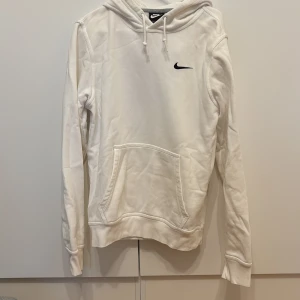 Vit hoodie från Nike - Säljer en vit hoodie från Nike med svart broderad logga på bröstet. Hoodien är S i Storleken men jag skulle säga att den passar som M. Väldigt bra skick i princip orörd. 
