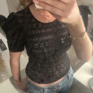 Svart spetsblus med puffärm - Så fin tröja, perfekt för fest! Knappt använd så är i väldigt bra skick! Storlek XS från Vila.