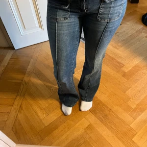 Blå bootcut jeans från Nelly  - Snygga blå jeans från Nelly  med bootcut passform och klassiska fickor både fram och bak. Jeansen har en låg  midja och är gjorda i slitstarkt denimmaterial. Jeansen är i mycket bra skick. Däremot är de upplagda passar mig perfekt som är ännu 1,55 🩷 därav priset, går att diskutera 