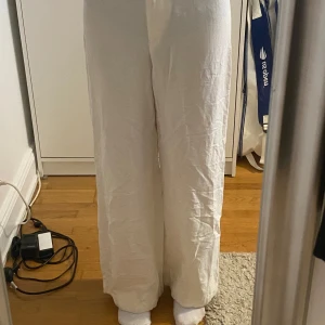 Vita linnebyxor i wide fit, strl 34 - Snygga vita linnebyxor i wide fit med rak passform. Byxorna är tillverkade i en blandning av viskos, linne och bomull vilket gör dem luftiga och perfekta för varma dagar. De har en enkel och stilren look som passar till allt. Använda en gång och provisoriskt uppsydda ca 3 cm.
