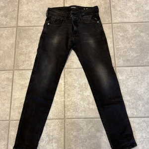 Svarta Replay jeans, 27/30 - Svarta jeans från Replay med snyggt tvättad look och klassisk femficksdesign. Modellen har normal midja och raka ben, med Replay-logga på fickan och bak. Perfekta till sneakers eller boots för en chill stil.