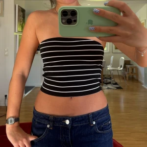 Svartvit randig bandeau tubtopp - Säljer en svart bandeau tubtopp . Toppen är croppad och sitter tight över bröstet