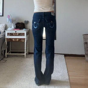Väldigt unika Lågmidjade true religon jeans - Snygga Lågmidjade True religon jeans. Med snygga detaljer på fickorna, utsydda. Midjemåttet tvärsöver är 38 cm och innerbenslängden är 85 cm. Något slitna längst ner men inget man lägger märket till.  Passar en storlek S eller XS