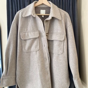 Beige overshirt från H&M i ullmix - Snygg beige jacka från H&M i storlek S. Säljer jackan då den inte kommer till användning längre. 