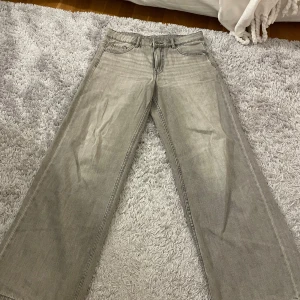 Grå wide jeans från Kappahl - Säljer ett par gråa jeans från Kappahl i storlek 164. De har en bred och rak passform med klassiska fem fickor och bälteshällor. Jeansen är tillverkade i jeansmaterial och har en cool, ljusgrå tvätt som ger en avslappnad vibe. Low Waist modell 