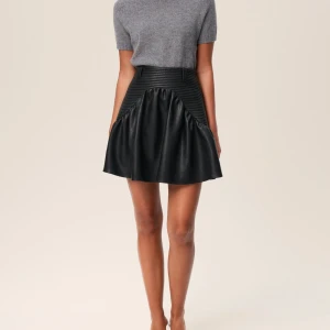 Svart kort kjol i skinn från Adoore - Supersnygg svart kort kjol från Adoore i skinnimitation med ribbad midja och coola volangdetaljer. Original pris: 1395 kr