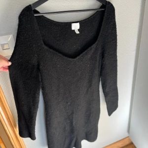 Svart stickad långärmad klänning - Mysig svart stickad klänning med lång ärm och djup v-ringning. Från HM, använd 1 gång. 
