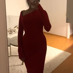 Röd ribbad one shoulder klänning - Säljer en tight, ribbad röd klänning från Gina Tricot. Klänningen har lång ärm, en snygg one shoulder-skärning och sitter figurnära. Lång klänning.