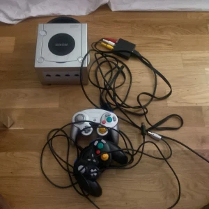 Nintendo Gamecube  - Klassiskt GameCube-spelpaket med Super Mario Sunshine! Inkluderar originalskiva, fodral och två handkontroller. Perfekt för dig som vill återuppleva nostalgiska äventyr eller upptäcka Mario-världen på nytt tillsammans med vänner.