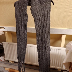 Mörkgrå stickad halsduk från L.O.G.G. - Säljer en lång och mysig mörkgrå halsduk från L.O.G.G. med grovstickad struktur och ribbad design. Halsduken har fransar i ändarna och är perfekt att svepa runt halsen för extra värme. Enkel och stilren look som passar till de flesta jackor.