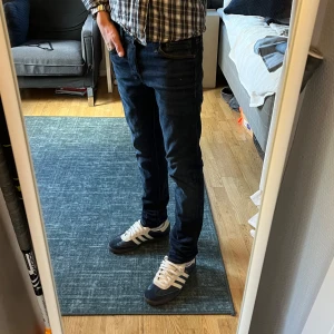 Mörkblå slim jeans Jack & Jones - Snygga mörkblå jeans från Jack & Jones i modellen Glenn. Jeansen är i nyskick! Jeansen har slim passform, klassisk femficksdesign och är tillverkade i stretchig bomullsmix för extra komfort. Perfekta för dig som gillar en smal siluett och stilren look.