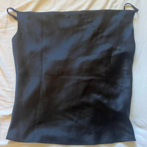 Svart satinlinne från Gina Tricot - Stilrent svart linne från Gina Tricot i glansigt satinmaterial. Linnet har tunna axelband och en rak, enkel passform som ger en clean look. Perfekt att matcha med jeans eller kjol för en trendig vibe.