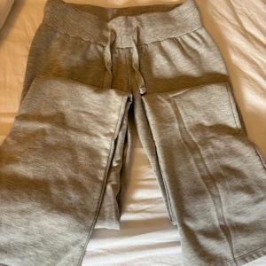 Gråa lowwaisted bootcut mjukisbyxor - Säljer ett par grå mjukisbyxor med bred resår i midjan och snörning framtill. Byxorna är i mjukt material och har en avslappnad passform, perfekta för chill dagar eller träning. Byxorna är lowwaisted bootcut. 