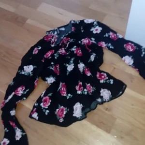 Blommig svart blus från H&M - Supersöt svart blus från H&M med stora rosa, röda och vita blommor. Blusen har långa ärmar och en snygg snörning framtill. Perfekt för dig som gillar romantiska vibes och vill sticka ut lite extra. Tunn och luftig, passar till både jeans och kjol. Det passar som en luftig xs eller en passande s/m. Tröjan är använd men har inga tecken på användning. 💕