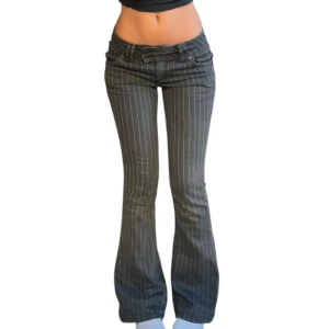Grå lågmidjade bootcut byxor - Snygga grå byxor med vita vertikala ränder och låg midja. Bootcut-modell som ger en schysst siluett och cool vibe. Perfekta för dig som gillar en trendig och avslappnad stil. Byxorna har klassiska fickor och knappstängning framtill.