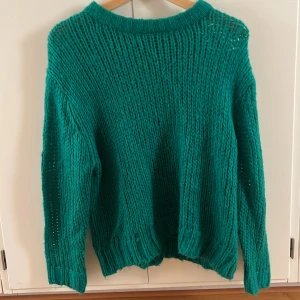 Grön stickad tröja från Sirup Copenhagen - Säljer en chunky stickad tröja i klargrönt från Sirup Copenhagen. Tröjan har en loose fit, bred ribbad mudd vid hals, ärmslut och nederkant samt långa ärmar. 