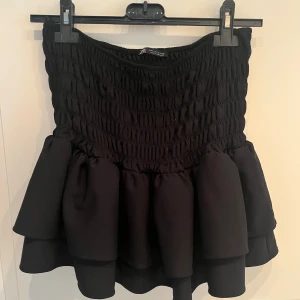 Svart volangkjol från Zara - Super fin svart volangkjol från Zara🫶🏼🫶🏼Liten i storlek och går att använda både som kjol och topp🥰