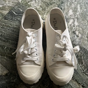Vita sneakers från Duffy - Snygga vita sneakers från Duffy med chunky platåsula och klassisk snörning. Skorna är i canvas med rund tå och har en stilren look som passar till det mesta. Perfekta för dig som gillar en clean och trendig stil. Använd max 3 gånger. 