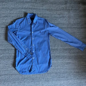 Ralph Lauren skjorta - Blå skjorta från Ralph Lauren med vita och mörkblå ränder. Slim fit-modell med klassisk krage och knappar framtill. Skick 9/10. Hör av dig vid minsta fundering! 