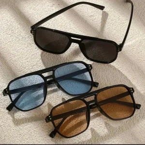 Svarta retro solglasögon i tre färger - Säljer tre par snygga retroinspirerade solglasögon med svart ram och stora fyrkantiga glas. Finns med mörkgrå, blå och orange tonade linser. Ramen är i lätt syntetmaterial och har en cool dubbelbrygga för extra stilpoäng. Perfekta accessoarer för att lyfta din look.Helt ny oanvänd. Vid retur står köparen för Frakten/Returen. Jag ansvarar inte för postens slarv.