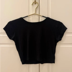 Svart croppad topp med kort ärm - Enkel svart croppad topp med rund halsringning och korta ärmar. Perfekt att matcha med höga jeans eller kjol för en chill och stilren look. Tunn och mjuk, passar bra till varmare dagar eller lager på lager.