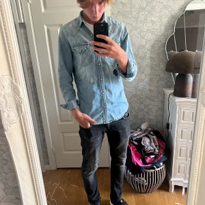 Jeansskjorta från Ralph Lauren Denim & Supply - Snygg ljusblå jeansskjorta från Ralph Lauren Denim & Supply i 100% bomull. Klassisk westernstil med två bröstfickor med knappar, långärmad och med tryckknappar framtill. Perfekt för dig som gillar avslappnad och cool stil.