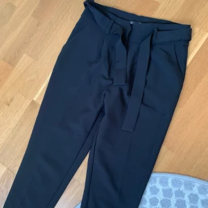 Svarta kostymbyxor med knytband - Snygga svarta kostymbyxor med knytband i midjan. Passar även S